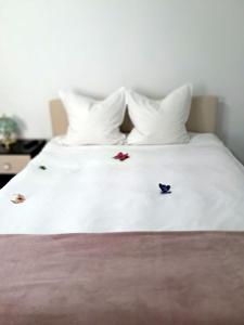 a white bed with white pillows and flowers on it at Căsuța galbenă in Bucharest
