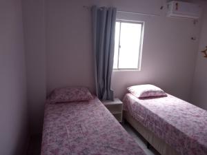 two beds in a small room with a window at Apartamento in Parnamirim