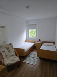 ein Zimmer mit zwei Betten, einem Stuhl und einem Fenster in der Unterkunft AlbFreizeit in Göppingen