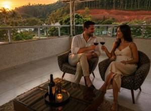 a man and woman sitting on a balcony drinking wine at Apartamento Charmoso e Tranquilo para sua Estadia in Vargem Alta