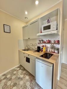 a kitchen with white cabinets and a microwave at Przy Parku Róż II in Chorzów