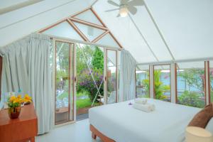 a bedroom with a white bed and a large window at Svargan Lakeside Glamping in Tabanan