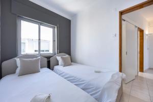 two beds in a room with a window at Incredible view - T2 Ribeirinha in Portimão