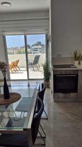 a living room with a glass table and a patio at דירת נופש נווה ים in Kefar HaNo‘ar Niẕẕanim