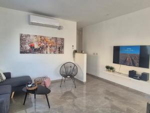 a living room with a couch and a tv on a wall at דירת נופש נווה ים in Kefar HaNo‘ar Niẕẕanim