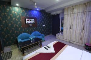 a hotel room with a bed and chairs and a tv at Hotel Yuvraj 5 Mints walking from Rajendra Nagar Metro Station in Ghaziabad