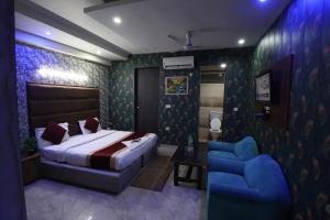 a bedroom with a bed and a blue chair at Hotel Yuvraj 5 Mints walking from Rajendra Nagar Metro Station in Ghaziabad +56 photos