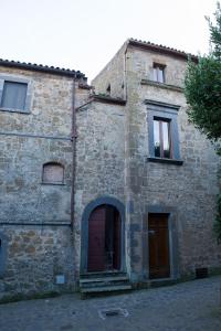 an old stone building with a red door and windows at Palazzo Contino in Bagnoregio