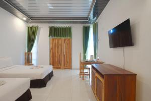 a room with two beds and a desk and a television at Pohon Purba Resort & Restaurant in Pulau Lebur