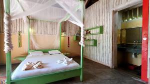 a bedroom with a green bed with a canopy at Bungalow Bleu Villa Luna Nosy Be in Nosy Be