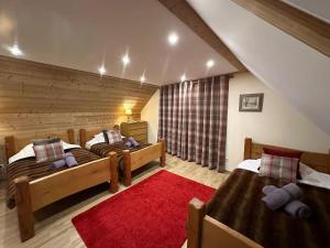 a bedroom with two beds and a red rug at L'Ancienne Poste Exclusive Alpine Chalet in Avajan