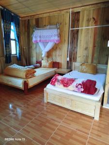 two beds in a room with wooden walls at Homestay Ngọc Thủy điểm dừng chân lên Đồi mâm xôi, xã Púng Luông, tỉnh Lào Cai in Mù Cang Chải