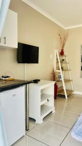 a living room with a desk with a tv on the wall at Hidden Bliss Guesthouse in East London
