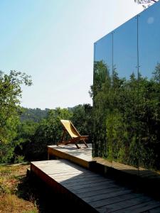 a glass house with a bench on a deck at Designer Cabin With Shared Pool In Bras in Bras