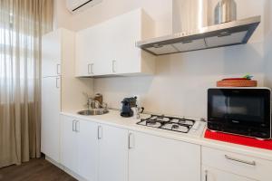a white kitchen with a stove and a microwave at Mazzini Urban Apartment - Lecce Selection in Lecce