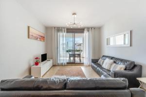 a living room with a leather couch and a television at Spacious 6-bed Apartment in Marina de la Alcaidesa in La Alcaidesa