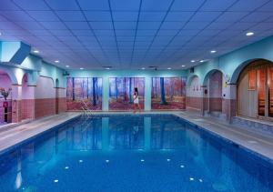 a woman is standing in front of a swimming pool at Dunalastair Hotel Suites in Kinloch Rannoch