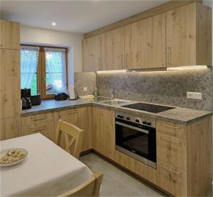 eine Küche mit Holzschränken, einem Herd und einem Tisch in der Unterkunft Haus Frechen in Berchtesgaden