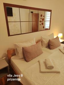 a white bed with pillows and a mirror on the wall at Vila Konak podno grejanje in Veliko Gradište