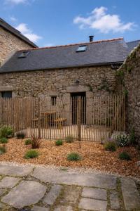 an old stone house with a wooden fence at Les campanules in Lanvénec