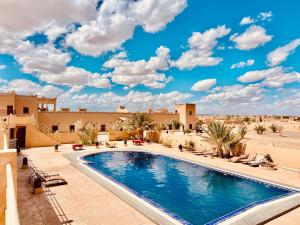 a pool in the middle of a desert with a blue sky at Les Roses Des Dunes in Merzouga