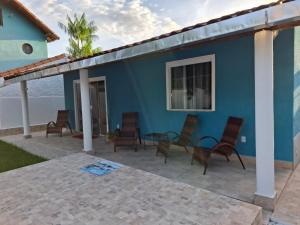 a blue house with chairs and a patio at Recanto do Sol em Marica in Maricá