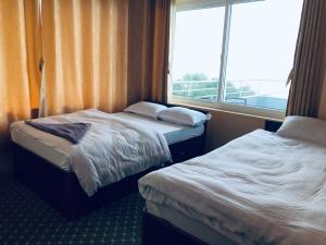 two beds in a hotel room with a window at Hotel New Manakamana in Pāti Bhanjyāng +3 photos