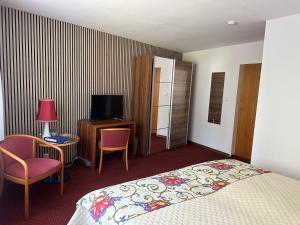 a hotel room with a bed and a television at Ohana Bed and Breakfast in Zorge