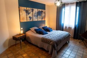 a bedroom with a large bed with blue pillows at L’Antre d’Eux in Carcassonne