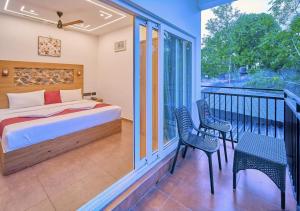 a bedroom with a bed and two chairs on a balcony at Nature Shade Pool Villa in Anachal +17 photos