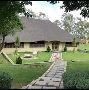 a white house with a large yard with a driveway at Folang Resort in Centurion