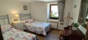 a bedroom with two beds and a desk and a window at Casa Belén Javierre de Bielsa in Bielsa