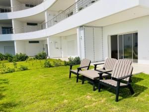 two chairs and a table on a lawn in front of a building at Apparemment s1 vu sur mer et piscine in Zarzis