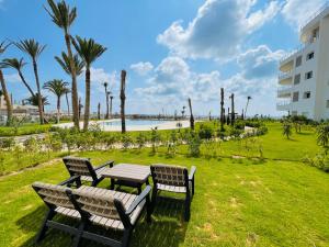 a picnic table and chairs in a park near the beach at Apparemment s1 vu sur mer et piscine in Zarzis