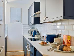 a kitchen with blue cabinets and a counter with food at Finest Retreats - Centre View in Sidmouth