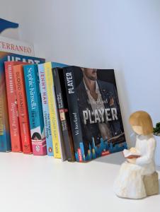 ein Regal mit Büchern und einer Buchfigur. in der Unterkunft CI VULIA B&B - Sicilia, con colazione, piscina, barbecue, parcheggio, free wifi, sea pool and bbq in Alcamo Marina