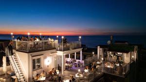 people sitting on the balcony of a building at night at Hotel La Giara in Cefalù