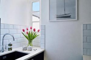 a kitchen with a sink and a vase of pink tulips at Finest Retreats - Centre View in Sidmouth +12 photos