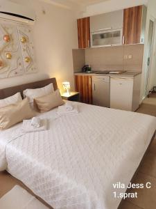 a bedroom with a large white bed and a kitchen at Vila Konak podno grejanje in Veliko Gradište