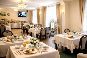 a restaurant with white tables and chairs with food on them at Zlatý Sloup in Karlovy Vary