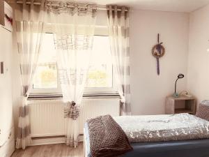a bedroom with a bed and a window with curtains at Pension Nazli Lübeck in Lübeck