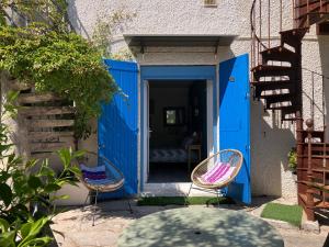two chairs sitting in front of a blue door at La cerisaie in Montpellier