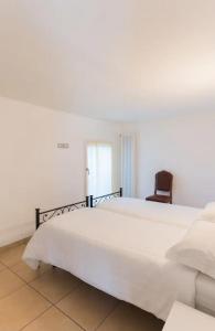 a bedroom with a large white bed and a chair at appartamenti ceccherini debora luna in Malcesine