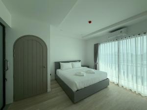 a bedroom with a bed and a large window at The View Hotel โรงแรมเดอะวิว นครศรีธรรมราช in Nakhon Si Thammarat