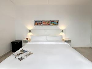 a bedroom with a white bed with a newspaper on it at Hotel Las Vegas in Calella