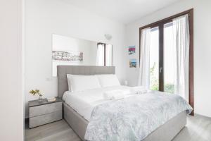 a white bedroom with a large bed and a window at EASYLIFE - Como - Crotta 3 - Argegno in Argegno