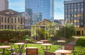 a garden with tables and chairs and a glass greenhouse at Hilton Milan in Milan