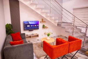 a living room with orange chairs and a tv at SARALIS Home in Abidjan +16 photos
