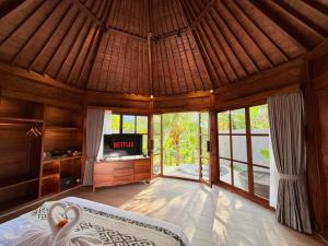 a bedroom with a bed and a tv in a room at Wanataru Sidemen Villas in Sidemen
