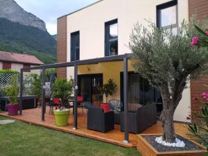 a house with a deck with a tree at Cocon au pied de la Chartreuse in Lumbin